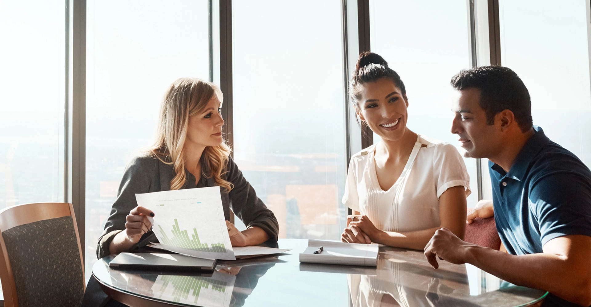Business meeting with three people discussing documents.